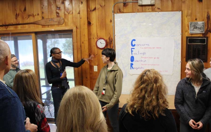 A person points at a whiteboard in front of a group of people during the family seminar of an outward bound intercept course.